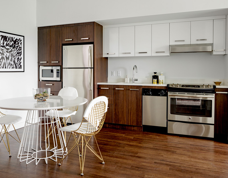 A clean and modern kitchen interior of a unit in Aster with a modern dinette and stainless steel appliances.